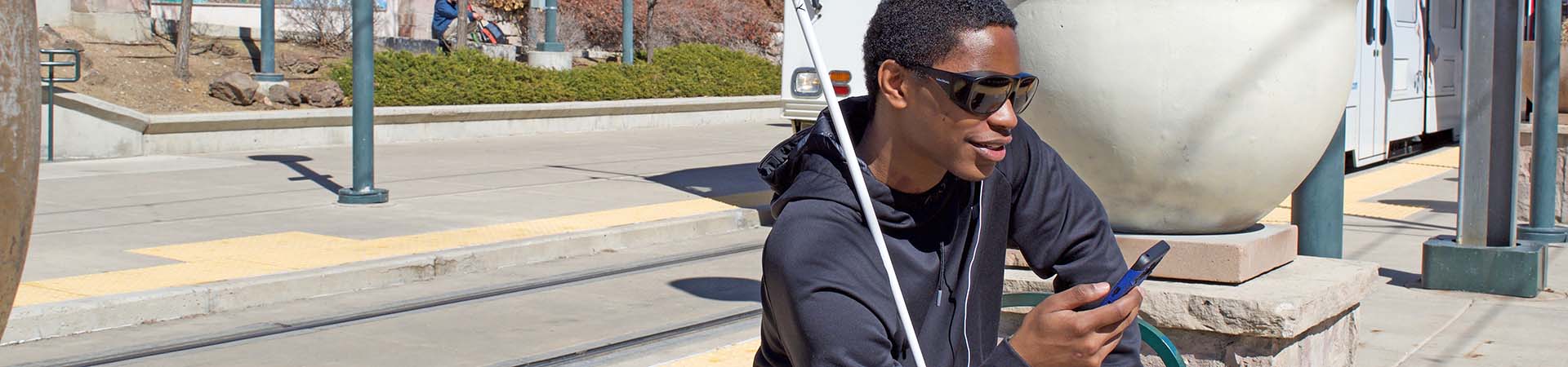 A man listens to his phone while waiting on a train
